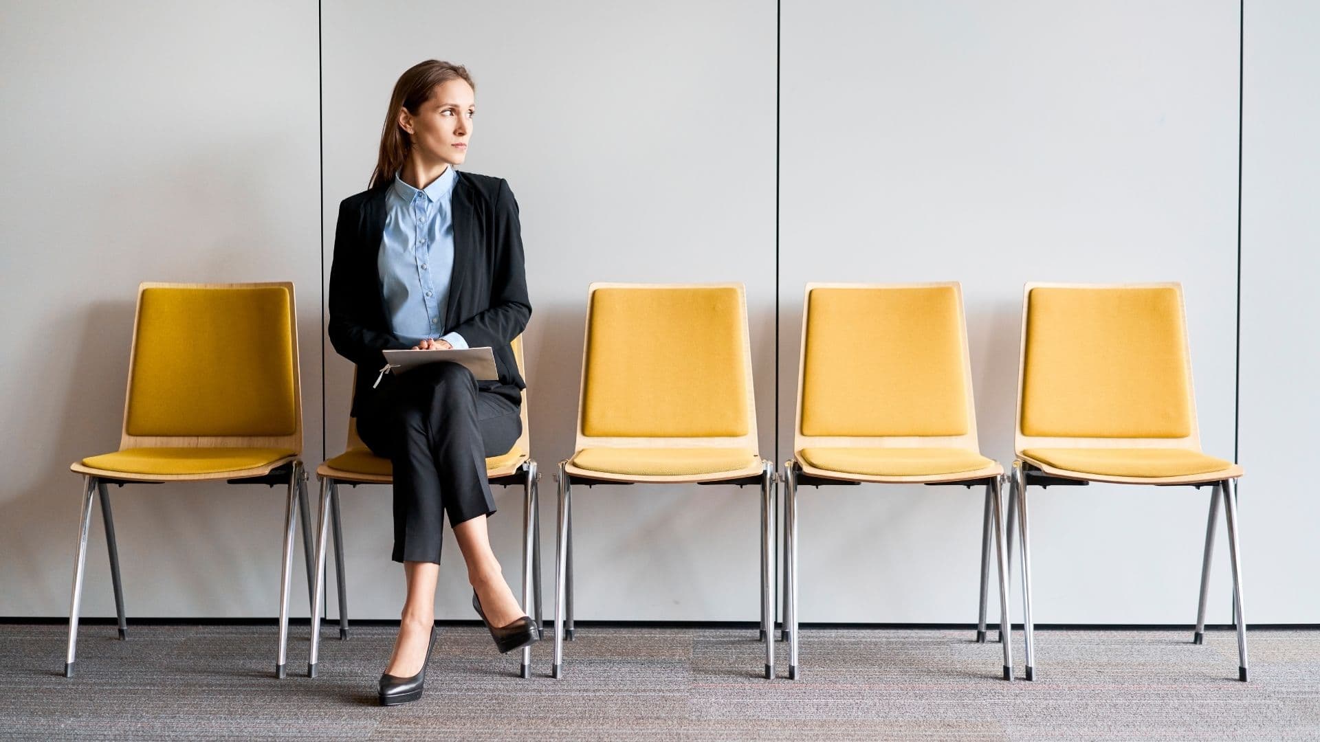 Business woman sitting in a row of 5 chairs with 4 chairs empty with the words Current Searches above her. 